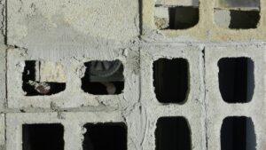 Gros plan de blocs de béton empilés en assises, leurs alvéoles creuses ouvertes sur le vide.