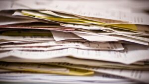 Une pile épaisse de documents papier empilés en désordre, feuilles jaunies et formulaires à copies carbone.