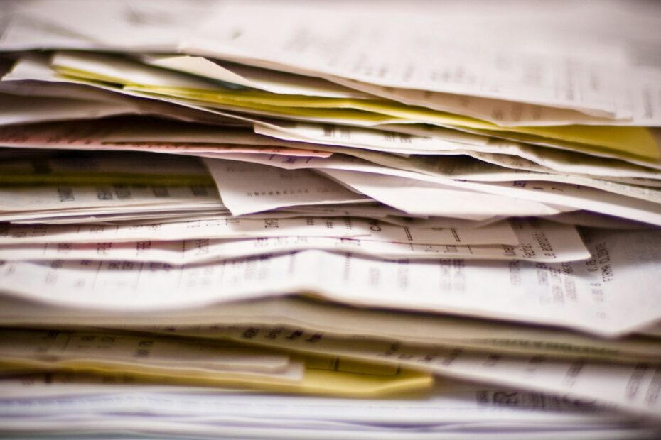 Une pile épaisse de documents papier empilés en désordre, feuilles jaunies et formulaires à copies carbone.